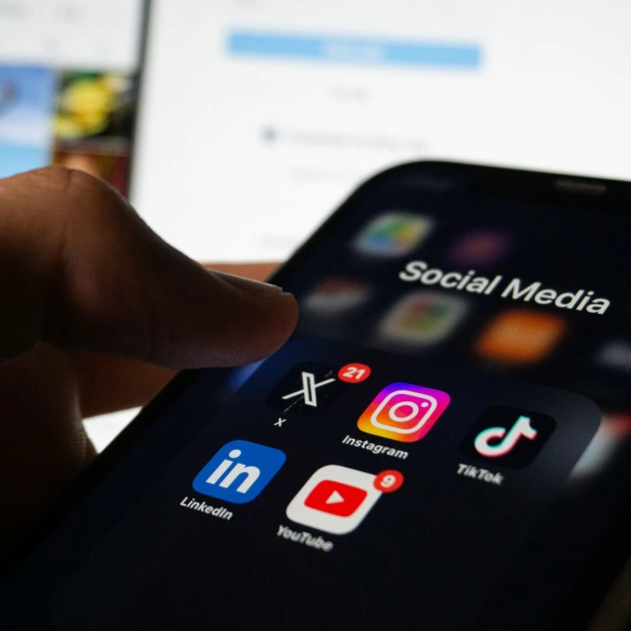 A person holding a smart phone with social media on the screen